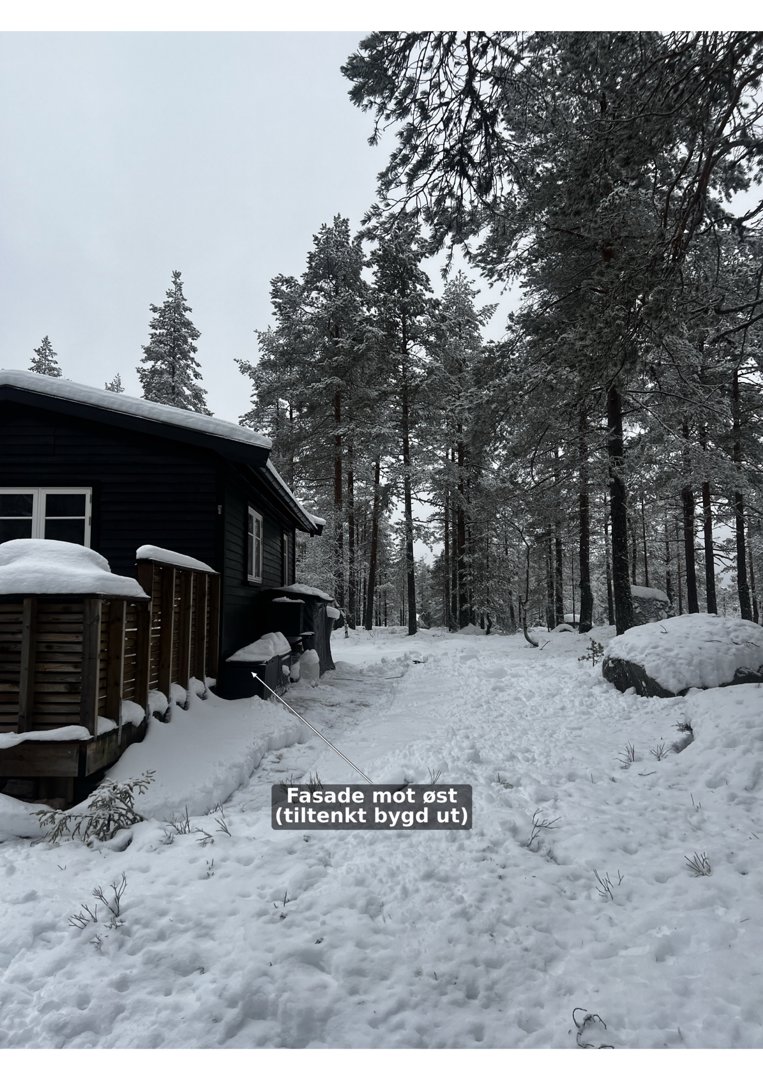 Fotografi av en hytte i snø med en tekstmerking som peker på fasaden.
