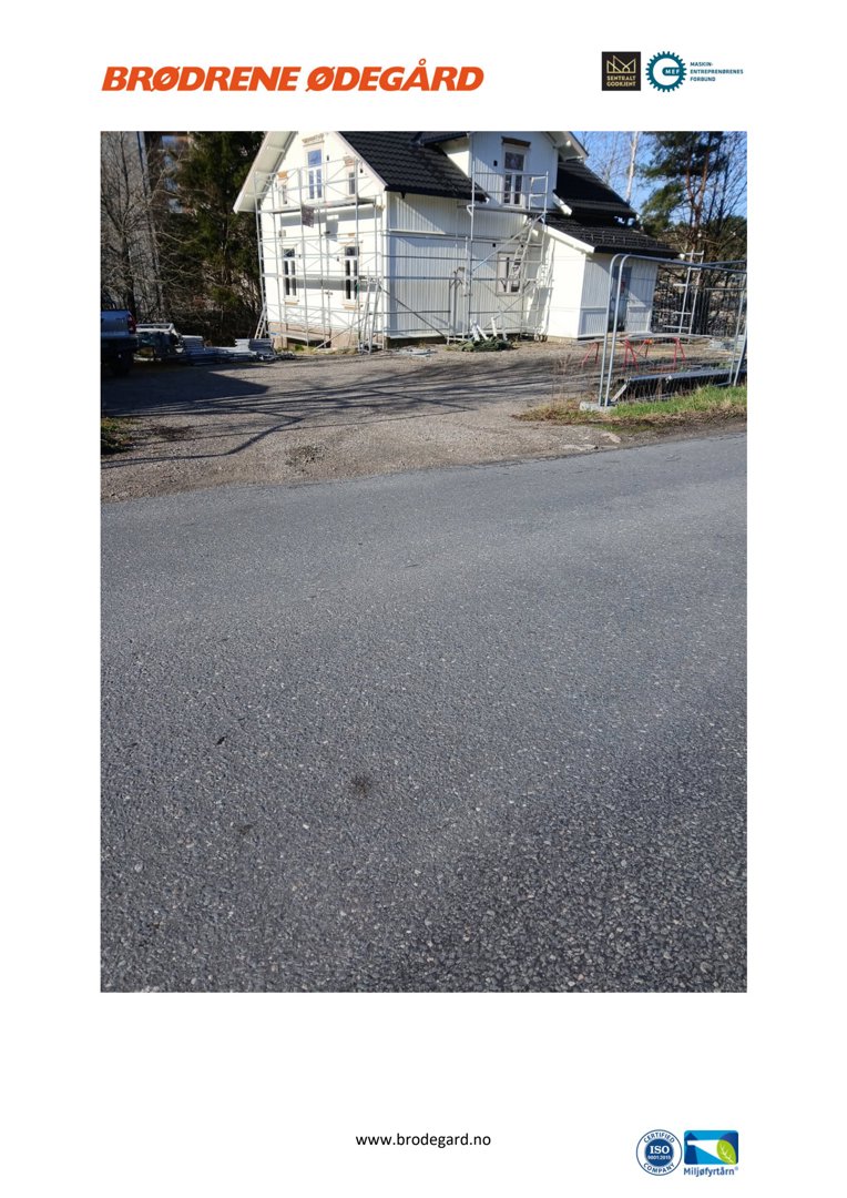 Fotografi av en hvit villa under oppussing eller vedlikehold, med stålrekkverk og en del av en vei i forgrunnen.