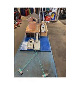 Fotografi av et fysisk arkitektonisk modell som viser en bygning, en kai og båter.