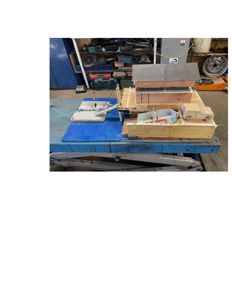 Fotografi av en fysisk arkitektmodell av en bygning, sannsynligvis en skole eller barnehage, plassert på en arbeidsbenk.