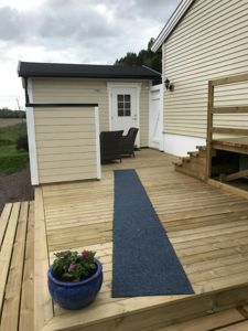 Fotografi av en uteplattform med trapp opp til en dør, en blå teppe og en blomsterpotte.