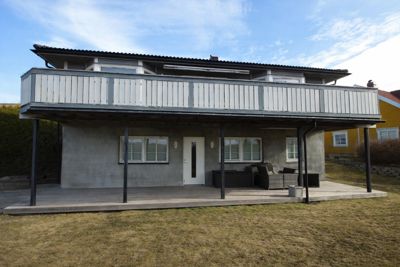 Fotografi av en toetasjes bolig sett fra bak/side, med en stor balkong på første etasje og en veranda under.