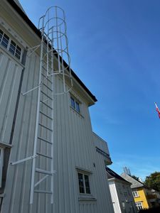 Fotografi av en hvit bygning sett fra nede, med fokus på en hvit branntrapp festet til fasaden.