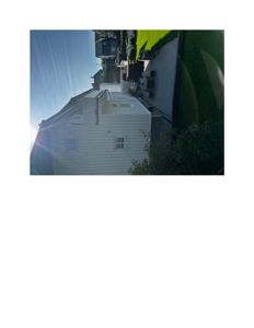 Fotografi av en hvit, toetasje villa sett fra siden, med en terrasse og hage i bakgrunnen.