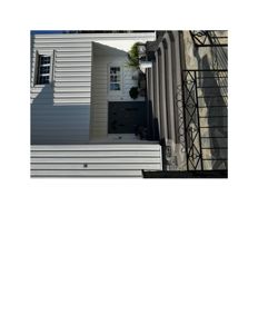 Fotografi av fasaden på en hvit bygning med en mørk inngangsdør, vinduer og en trapp opp til inngangen.