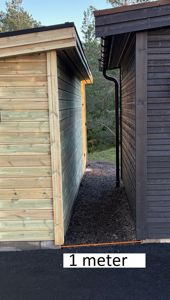 Fotografi av to bygninger sett fra siden, med en markert avstand på 1 meter mellom dem.