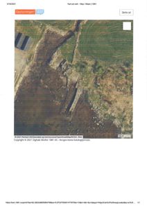 Flyfoto eller satellittbilde av et område med en bygning og omgivende terreng, inkludert skog og åker.