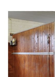 Fotografi av en innvendig vegg med trepanel og metallramme, sannsynligvis i en garasje eller uthus.