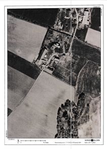 Flyfoto eller ortofoto av et landbruksområde med bygninger og vegnett.