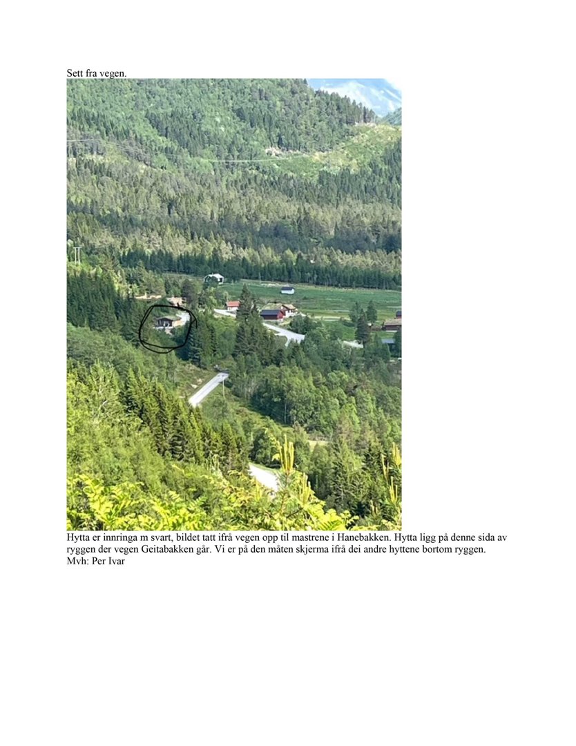 Fotografi av en hytte sett fra veien opp til mastrene i Hanebakken, med omgivende natur og andre hytter i bakgrunnen.