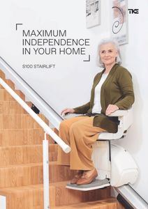 Fotografi av en eldre kvinne som sitter i en trappelyft (stairlift) på en trapp.