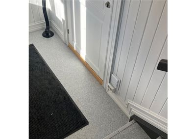 Fotografi av en inngangsparti i en bolig, som viser gulv, dør, trinn og en del av en lampe.