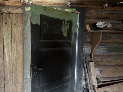 Fotografi av en gammel, mørk dør i en loggbygnings innsiden.