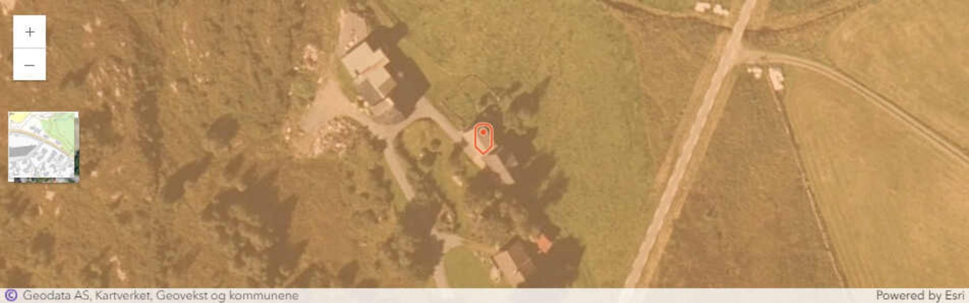 Satellittbilde (flyfoto) av et område med eiendom, vei og skog, med kartkontroller og logoer.