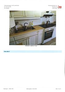 Fotografi av et kjøkken med hvite sotskader, hvite skap, en dobbeltvask, en kaffekvern og en hvit ovn.