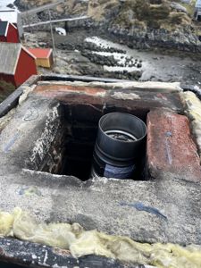 Fotografi av en takkonstruksjon med isolasjon og en metallrørledning (t.d. for ventilasjon eller nedløp) som går gjennom taket.