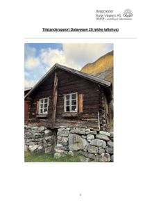 Fotografi av en gammel laftehytte med steinfundament, tatt utendørs.