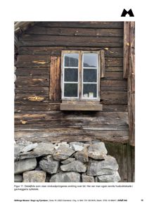 Et fotografi som viser en detalj av en gammel tømmerbygning, inkludert et vindu, en steinmur og en sylstokk.