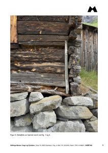 Et fotografi som viser en detalj av en gammel tømmerbygning, inkludert hjørnekonstruksjon og steinfot.