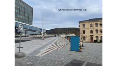 Fotografi av Strømsø Torg med bygninger, trapper og et reklameskilt.