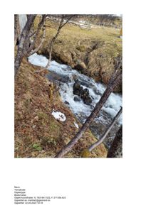 Fotografi av en bekke eller elv med vann som renner over steiner, omgitt av skog og snøflekker. Bildet har metadata nederst.