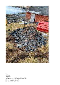 Fotografi av en byggeplass med en stor haug av utgravet jord og stein i forgrunnen, en rød skur i bakgrunnen og vann med båter i horisonten.