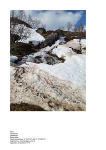 Fotografi av en snødekt bakke med en liten bekke eller vannstrømning.