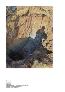 Fotografi av en utgravd grøft eller fundamenteringsgrøft med synlig jordprofil og skygge fra en person.