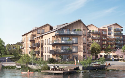 3D-visualisering av et planlagt boligkompleks med trefasade, beliggende ved vann.