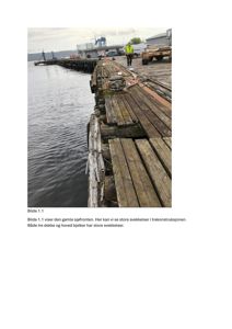 Fotografi av en gammel, forfallende trekonstruksjon (sjøfronten) med en person i sikkerhetsutstyr som står på den.