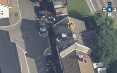 Flyfoto eller satellittbilde av et boligområde med en bygning markert med en gul sirkel.