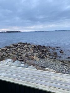 Fotografi som viser utsikt fra en terrasse eller veranda mot vannet og en kystlinje.