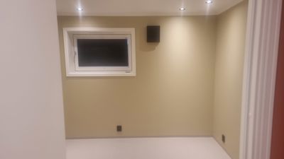 Fotografi av et tomt, innredet rom med gulvegg, vindu og taklys.