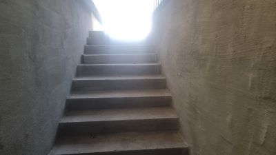 Fotografi av en betongtrapp som leder opp til et lysere område.