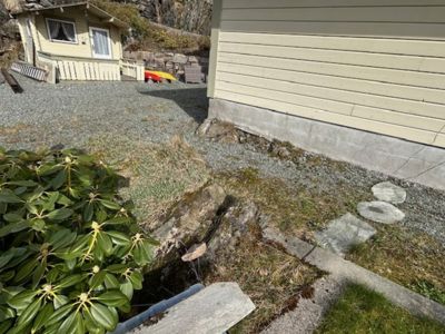 Fotografi av en bygning sett fra siden, med synlig fasade, fundament og omgivende terreng.