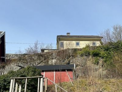 Fotografi av en gul bygning på en klippeskrent, sett fra nede.