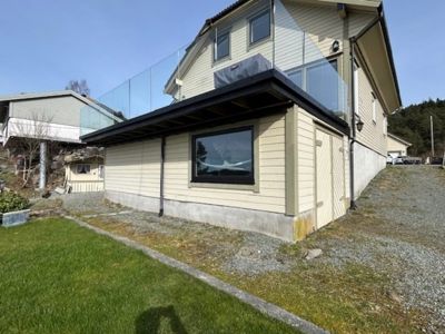 Fotografi av en eksisterende eller ferdigstilt enebolig sett fra siden, med fokus på fasade, tak og grunnmur.