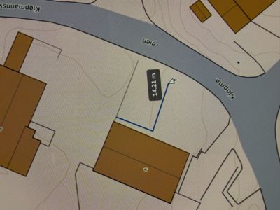 Situasjonsplan som viser tomt, bygninger, veier (Kjøpmannsgata, -veien) og en målt avstand (14,21 m) mellom to punkter.