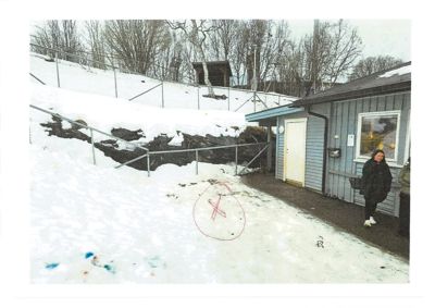 Fotografi av en eksisterende bygning (hus) sett fra siden, med snø på bakken og en person som står på verandaen.