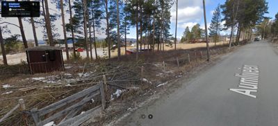 Fotografi av en vei (Aumlieveien) med skog og en liten hytte i venstre side.