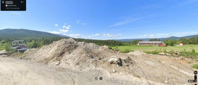 Fotografi fra Google Street View som viser et utgravd område med en stor jordhaug i forgrunnen, en moderne villa til venstre og en rød gård i bakgrunnen.