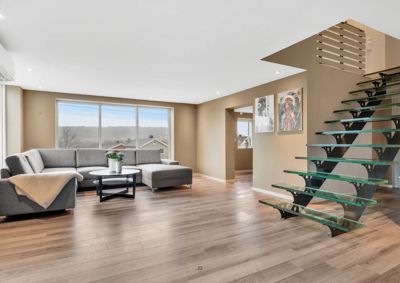 Fotografi av et moderne stueområde med en glass- og metalltrapp.