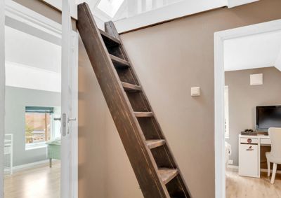 Fotografi av en inngangsplass med en bratt tretrapp som leder opp til en loftsetasje.