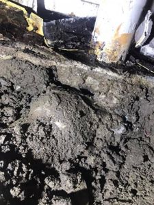 Fotografi av en byggeplass eller undergrunn, som viser jord, en betongkonstruksjon og en metallrørledning.