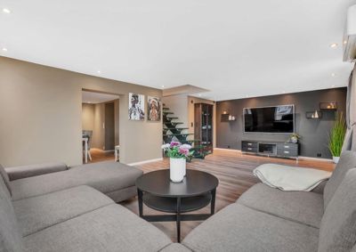 Fotografi av et innredet stueområde med sofaer, TV og trapp.