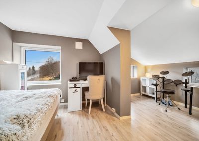 Fotografi av et innredet soverom med skrivebord, senger og trommesett.