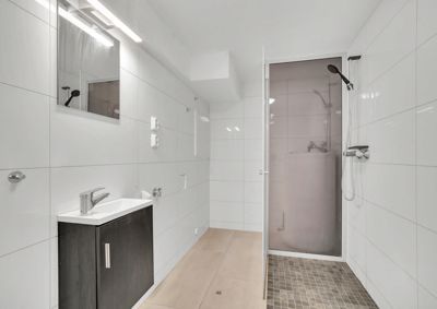 Fotografi av et moderne, innredet bad med dusj, vask og speil.