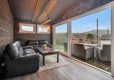 Fotografi av et innendørs rom med møbler og utsikt til en terrasse.