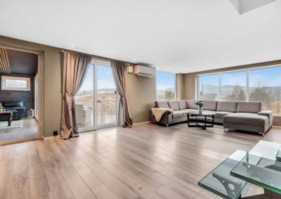 Fotografi av et innredet stueområde med store vinduer og utsikt over fjell.