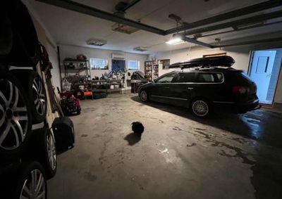 Fotografi av en garasje med en bil og diverse gjenstander.